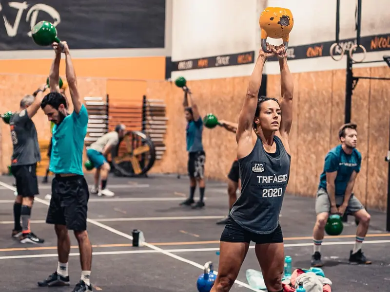 Classe fent swings amb kettlebell per sobre del cap