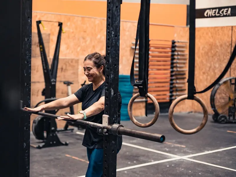 Atleta somrient mentre fa un exercici amb barra i anelles