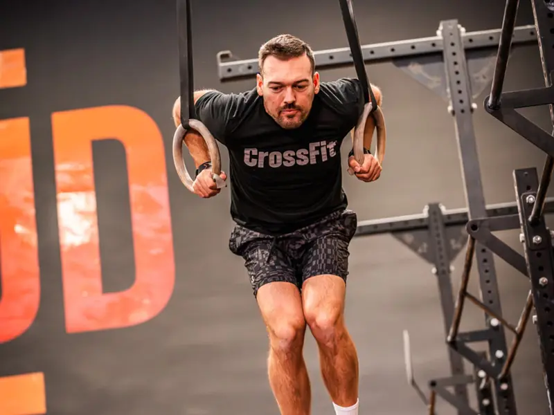 Atleta fent un exercici a les anelles en una classe de WOD