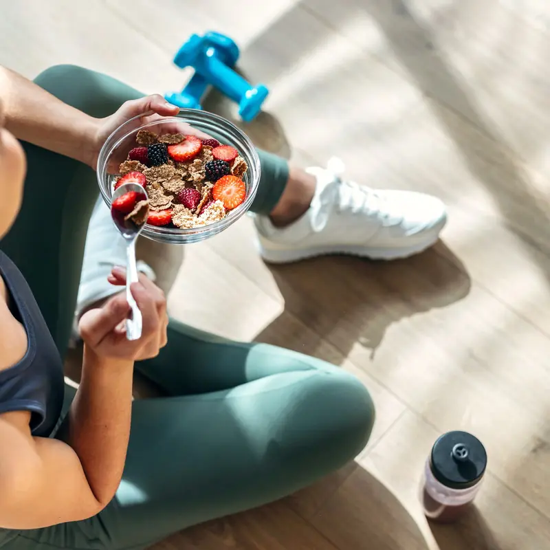 Bol de iogurt amb fruita i cereals al costat d'unes manuelles